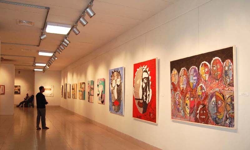 A man standing and viewing an art exhibition. 