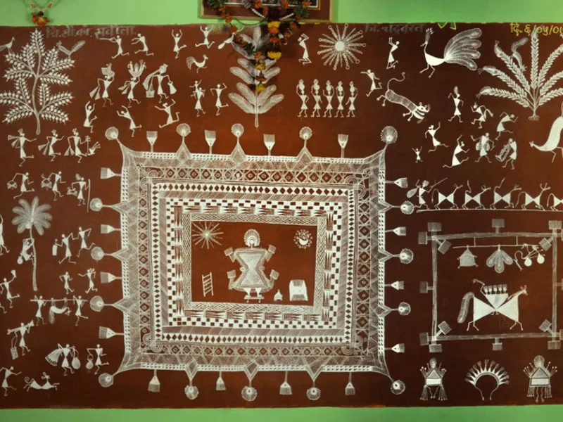 A traditional Warli painting done in white over a red ochre background. Panchasiriya is in the dev chauk in the bottom right of the picture. there is a lagna chauk in the centre.