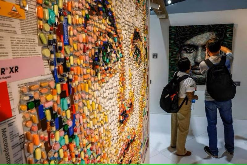 A COP27 delegate takes photos of a portrait by Turkish artist Deniz Sagdic.
